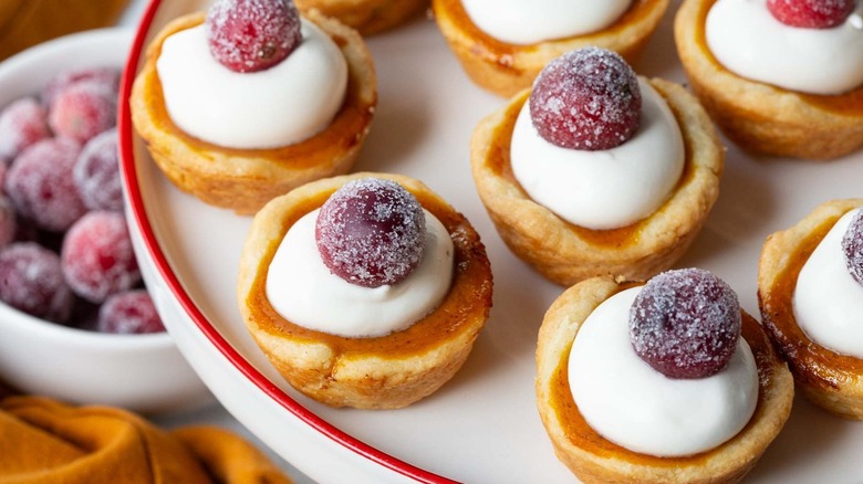 miniature tarts topped with whipped cream and sugared cranberries