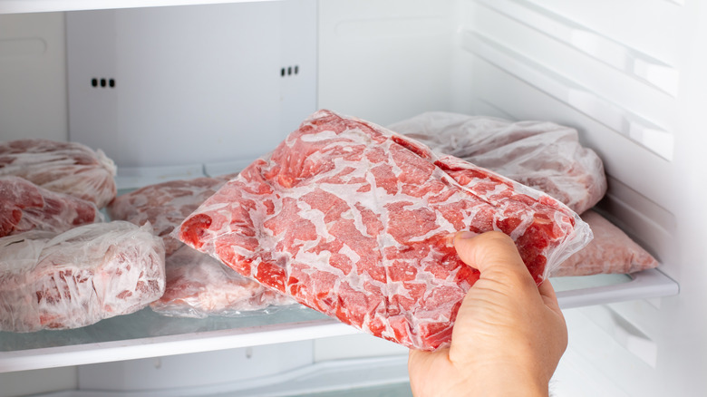 hand pulling frozen meat out of freezer