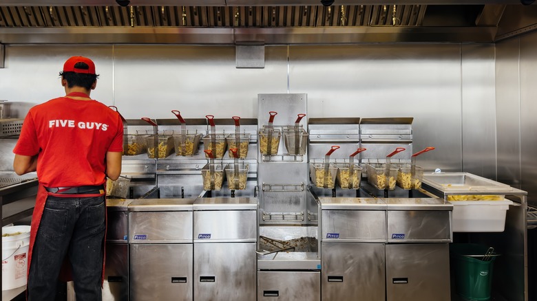 Worker frying french fries at Five Guys 