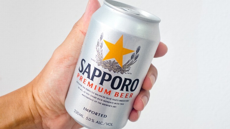 Sapporo Beer can in hand