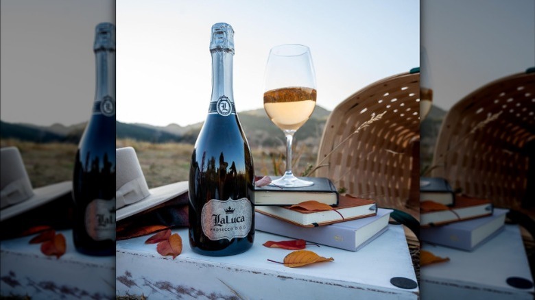 bottle and glass of la luca prosecco on outdoor table with books