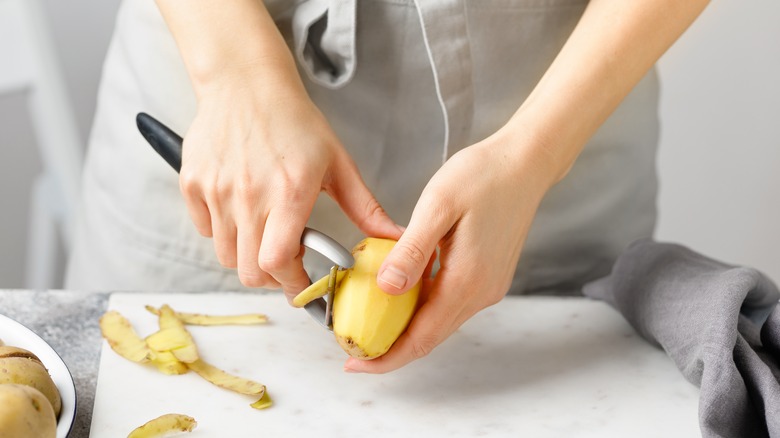 Person peeling potatoes