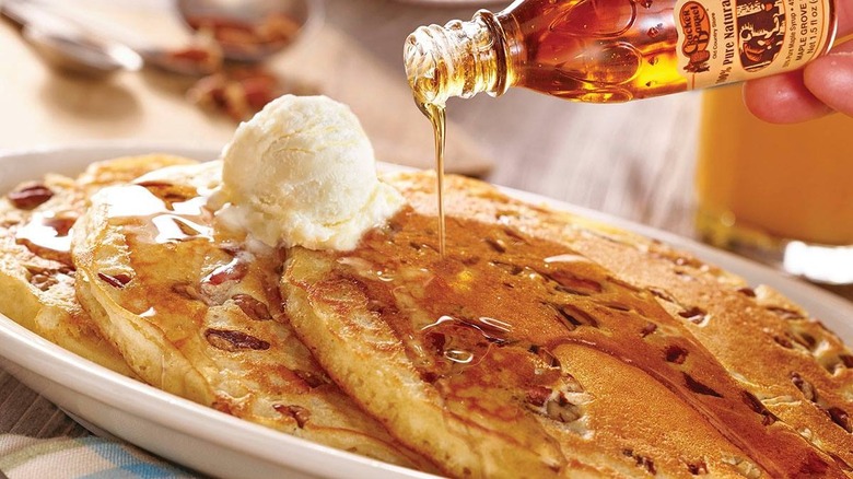 pouring syrup on pecan pancakes