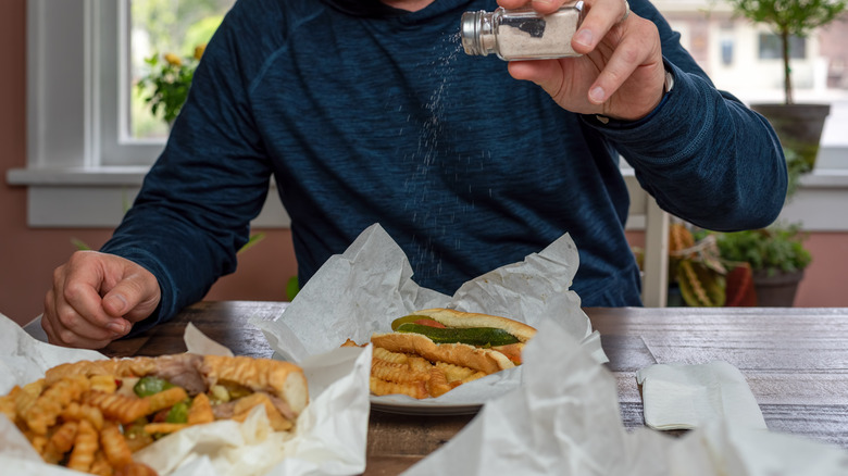 Man salting hot dog fries