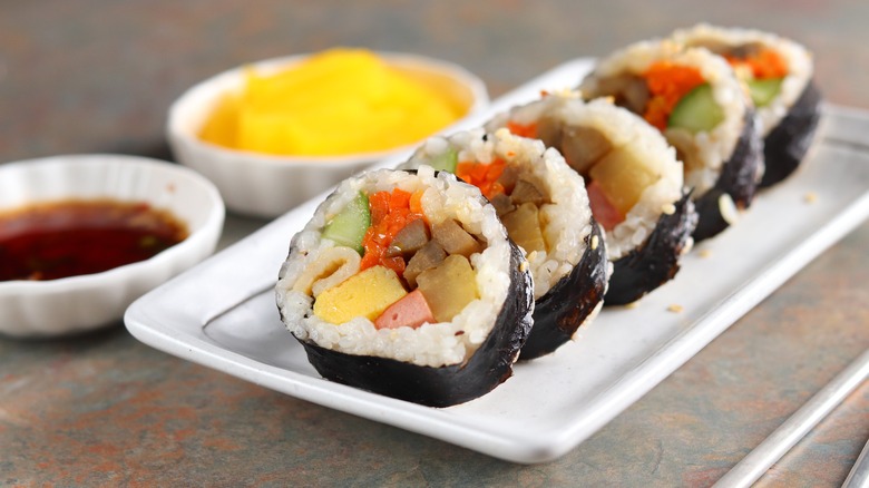 sliced kimbap roll next to sauces