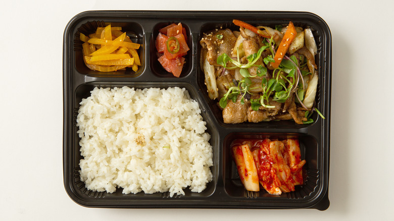 black lunch box with rice and other sections