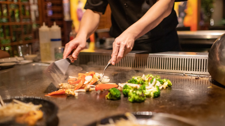 chef cooking veggies on open metal grill