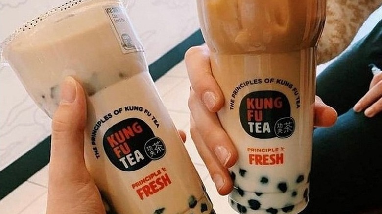 Hands holding Kung Fu Tea drinks