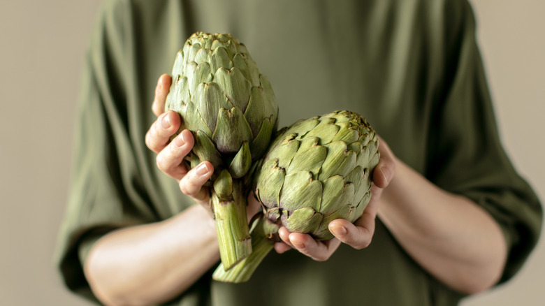 woman holding two artichokes