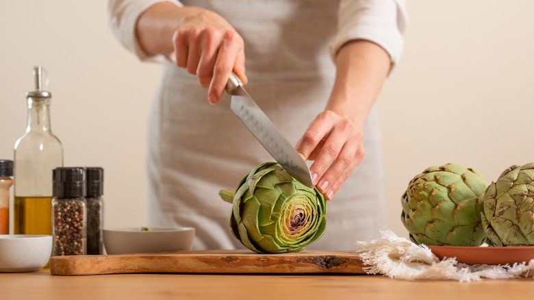 person cutting artichoke with knife