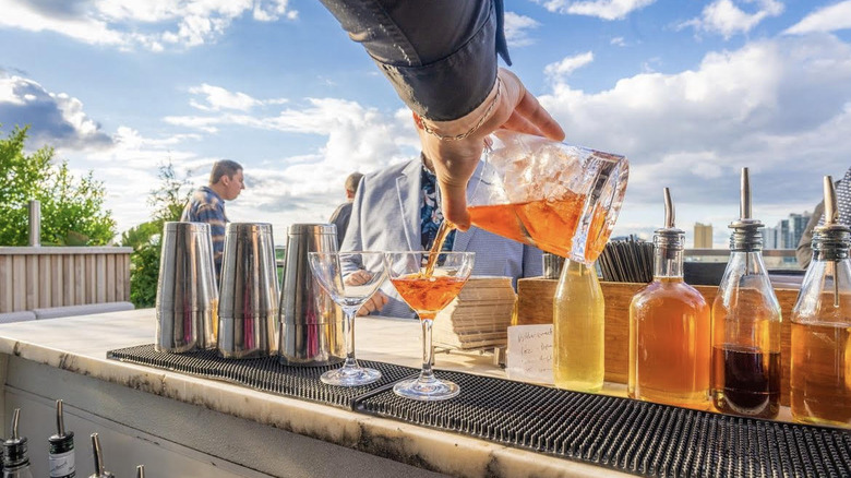 Hand pouring drinks at bar