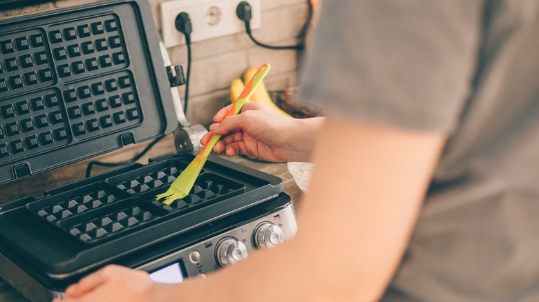 Person greasing a waffle maker