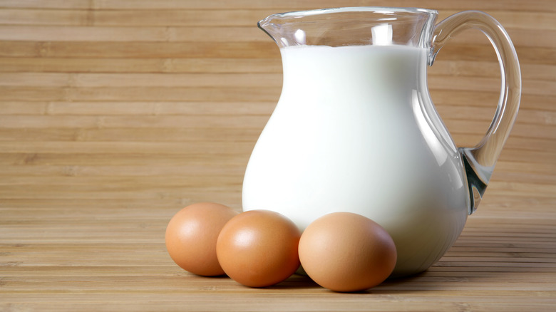 A jug of milk with three eggs