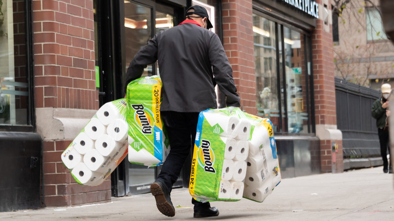 man with several packs of paper towels