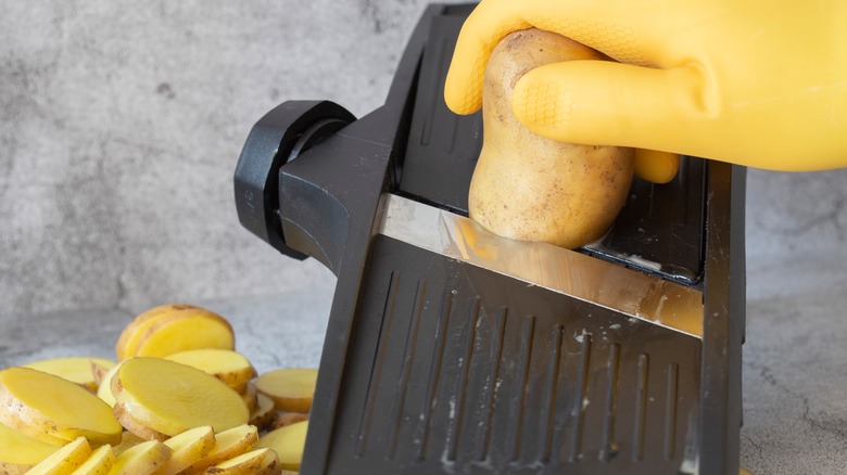 Peeled potato against mandolin slicer 