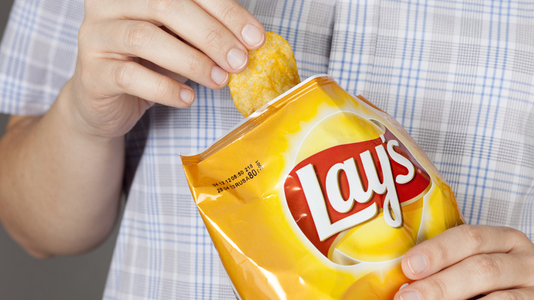 person eating from a bag of Lay's Classic potato chips