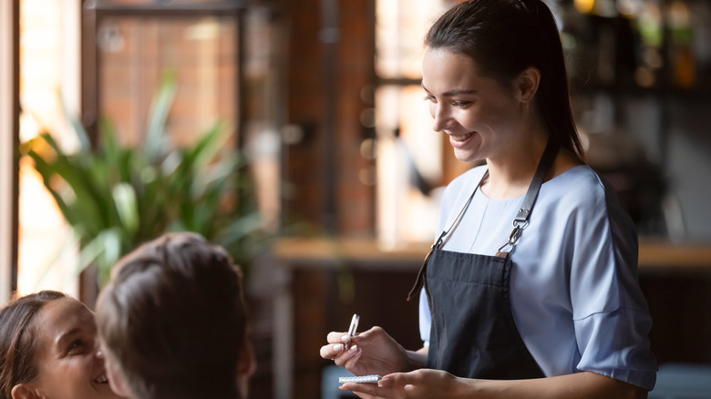 smiling server taking customer orders in a restaurant