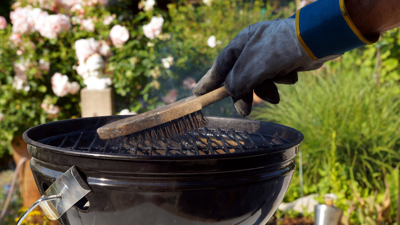 person cleaning grill with brush