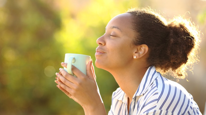 Woman inhaling aroma from cup