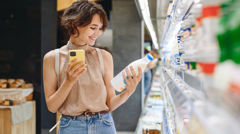 woman holding smartphone while shopping