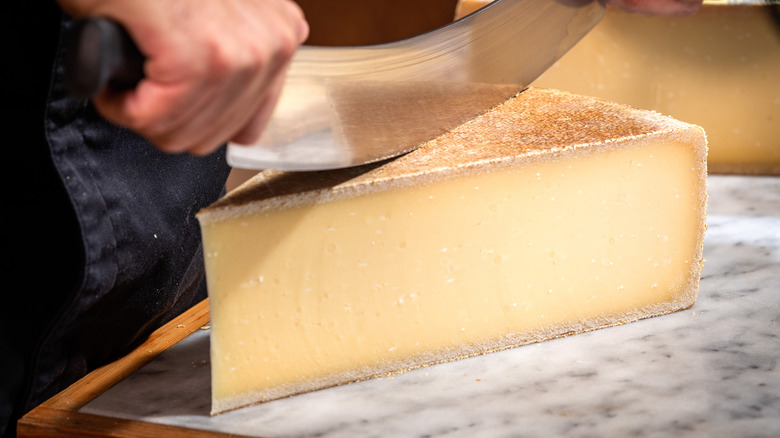 Block of Gruyere cheese being sliced