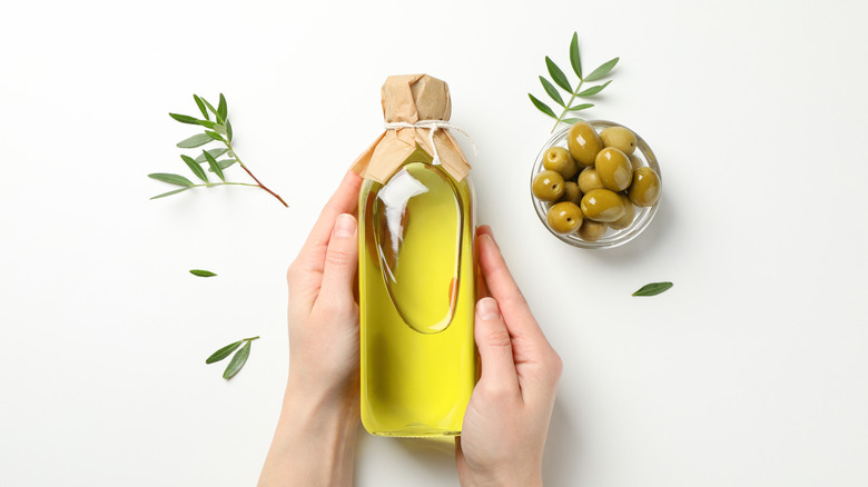 female hands holding an olive oil bottle