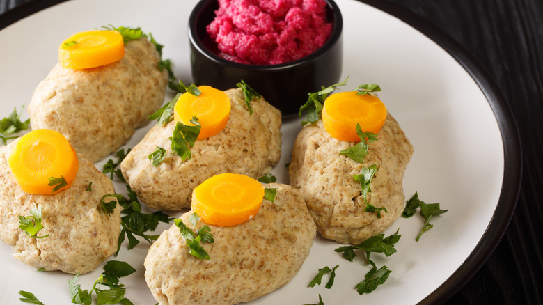 Pieces of gefilte fish on a white plate with horseradish in a ramekin