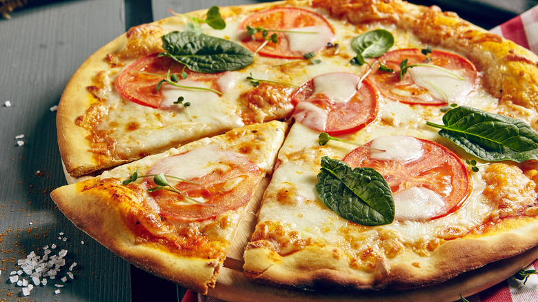 Close up of a pizza with tomato slices and basil