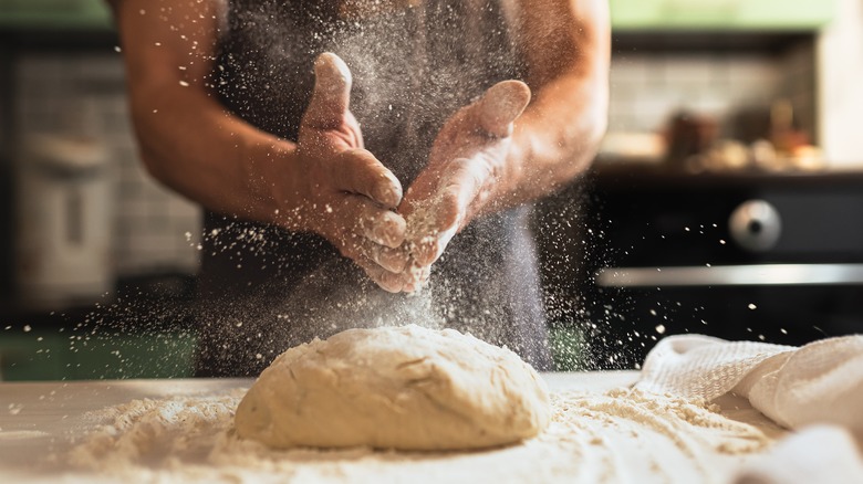 Person flouring pizza dough