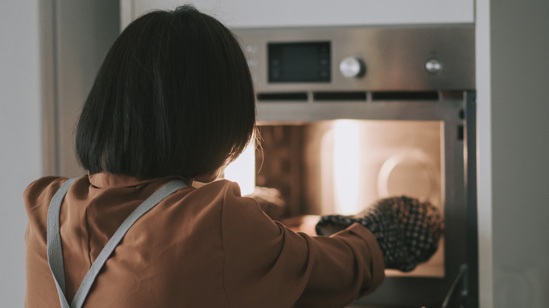 person putting food in oven