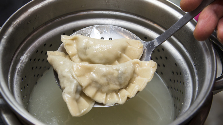 boiled dumplings being lifted from a pot