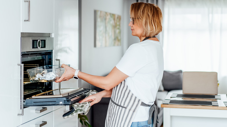 woman putting dish in oven