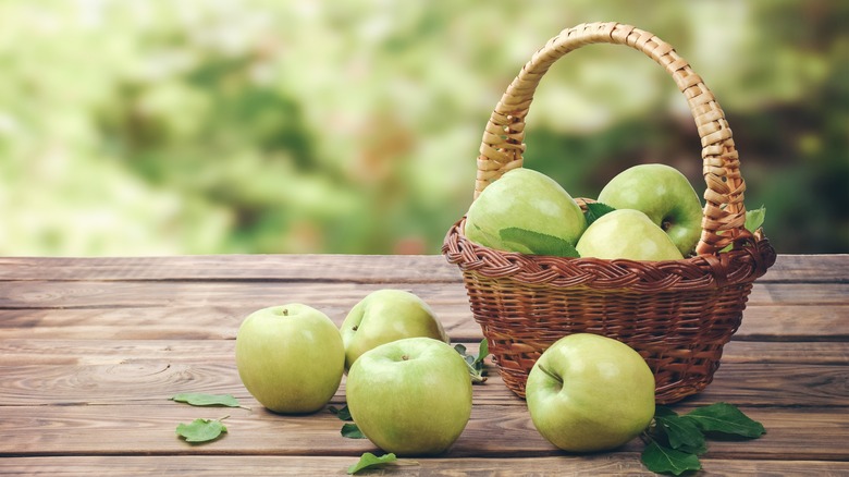 Green apples in basket on table 