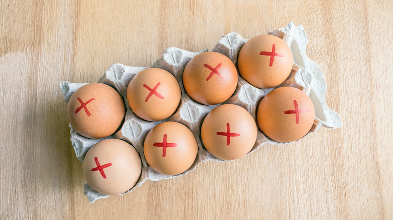 Carton of brown farm eggs, with a red cross drawn on the top of each one