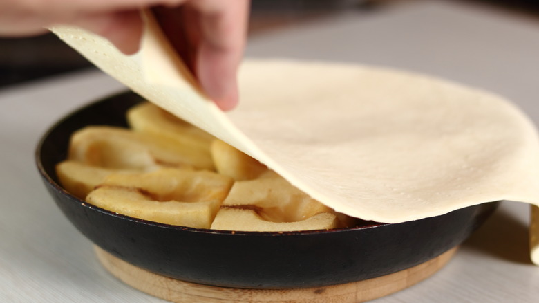 Placing puff pastry on top of tarte Tatin