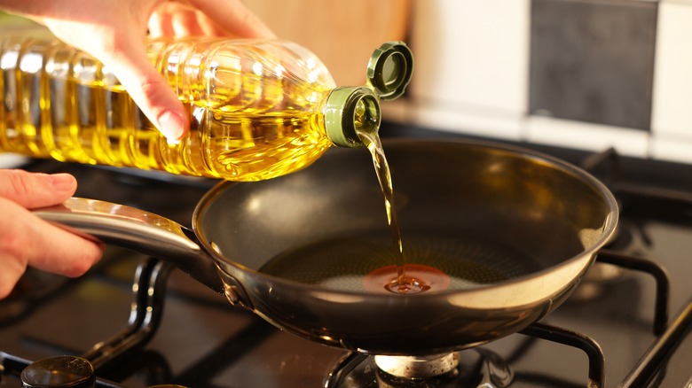 Hand pouring oil in pan 