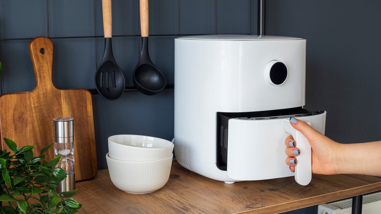 woman using air fryer on countertop 