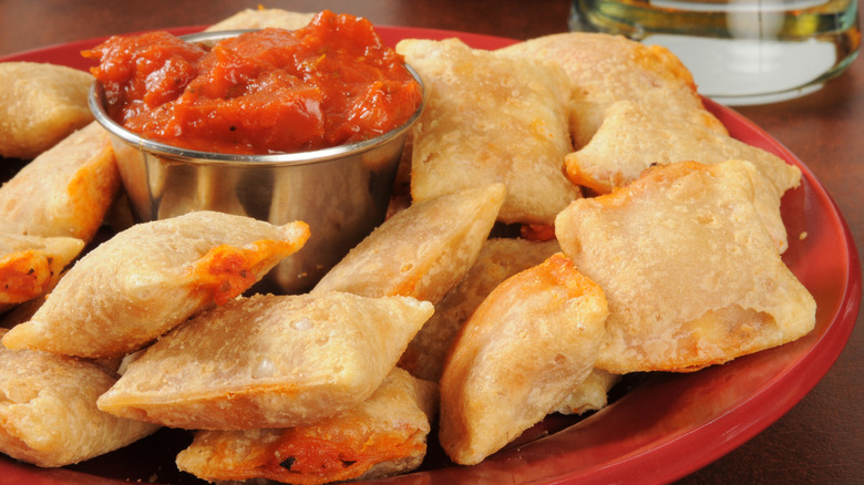 Pizza rolls served on plate with bowl of marinara