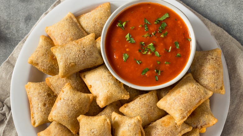 Pizza rolls on plate with sauce in ramekin