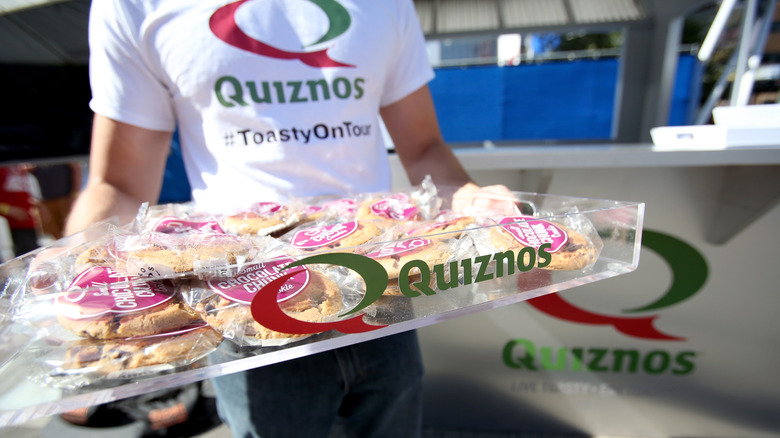 Quizno's employee holding cookie tray