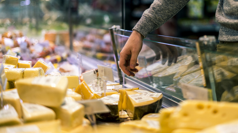 person choosing a cheese at a store counter