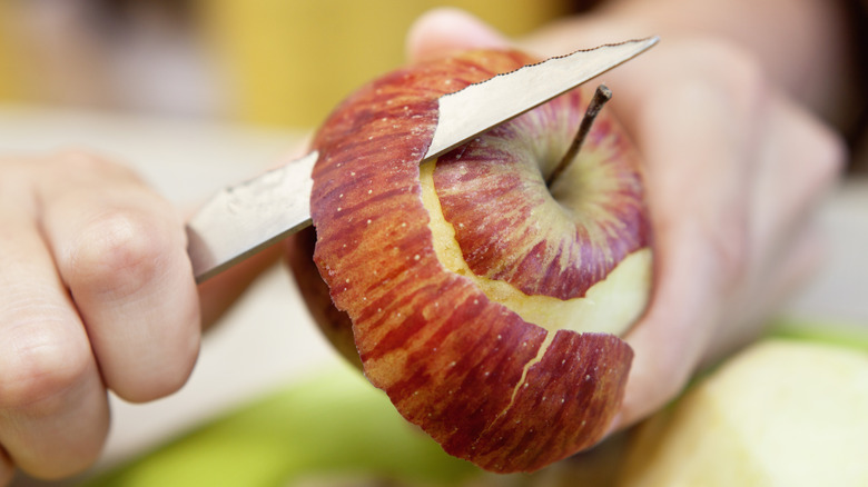 person peeling apple with knife