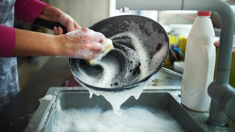 person washing pan in sink