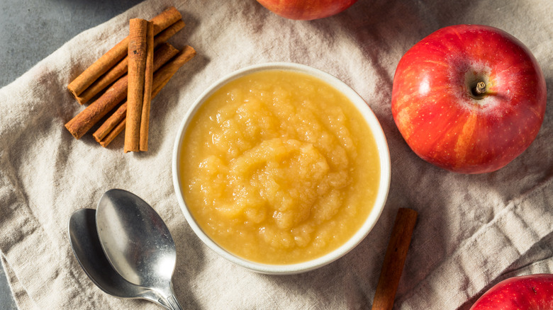 overhead shot of a bowl of applesauce with apples and cinnamon sticks