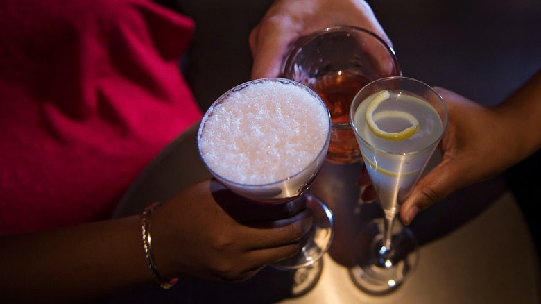 Hands toasting with colorful cocktails