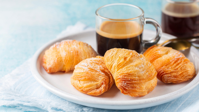 A plate of sfogliatelle riccia with a cup of espresso