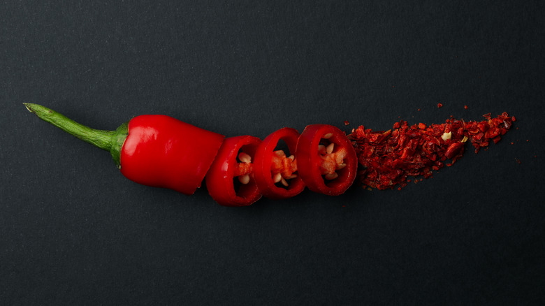 red chili pepper sliced and ground on a black surface