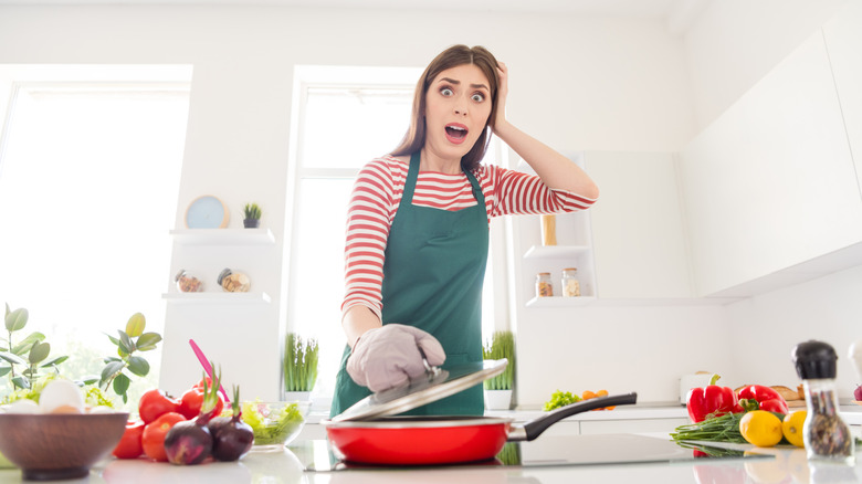 upset woman cook pan with vegetables
