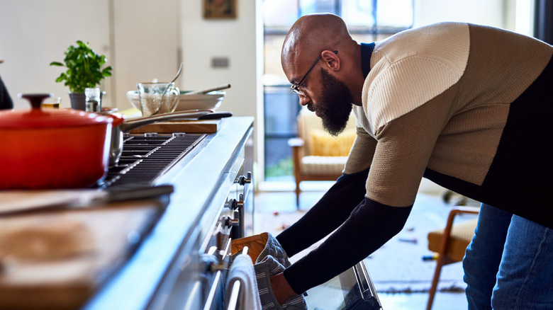 man placing dish in oven