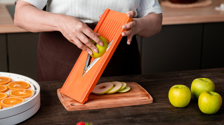 Hand slicing apples on mandoline.